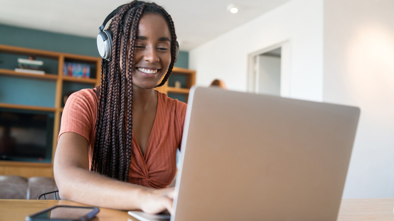 Uma mulher em seu escritório em casa participa de uma reunião online, demonstrando uma excelente Postura no Trabalho Remoto, tema do novo curso da Scooto Academy.